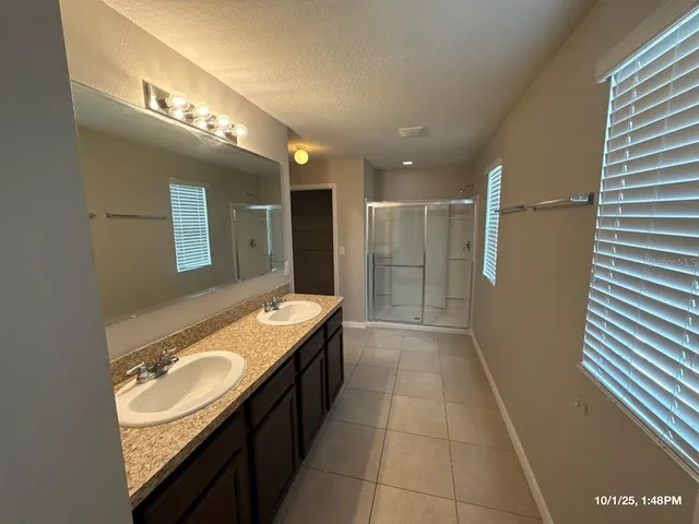 a bathroom with a granite countertop sink a large mirror and a shower