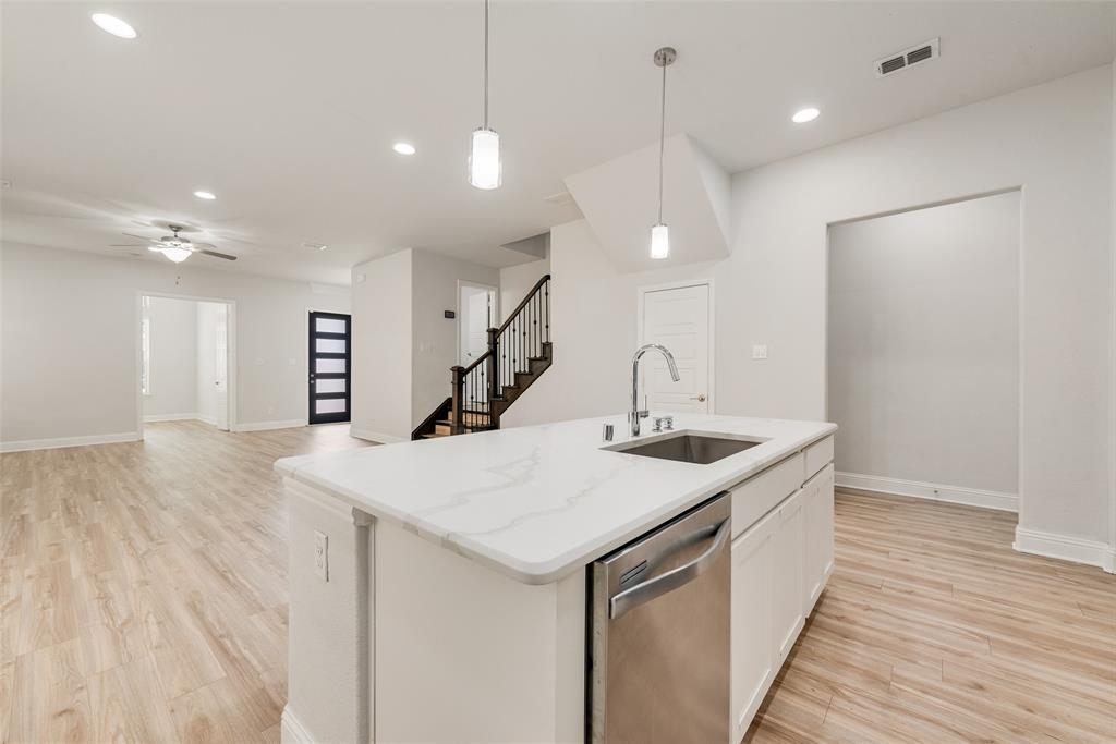 628 Ansley Way Allen, TX 75013 - Photo 4 of 20 Kitchen island with a white stone countertop, undermount sink, and stainless steel dishwasher