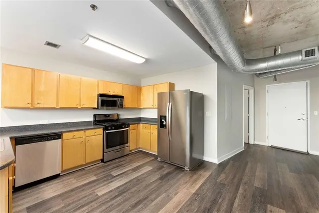 a large kitchen with stainless steel appliances granite countertop a lot of counter space and wooden floors