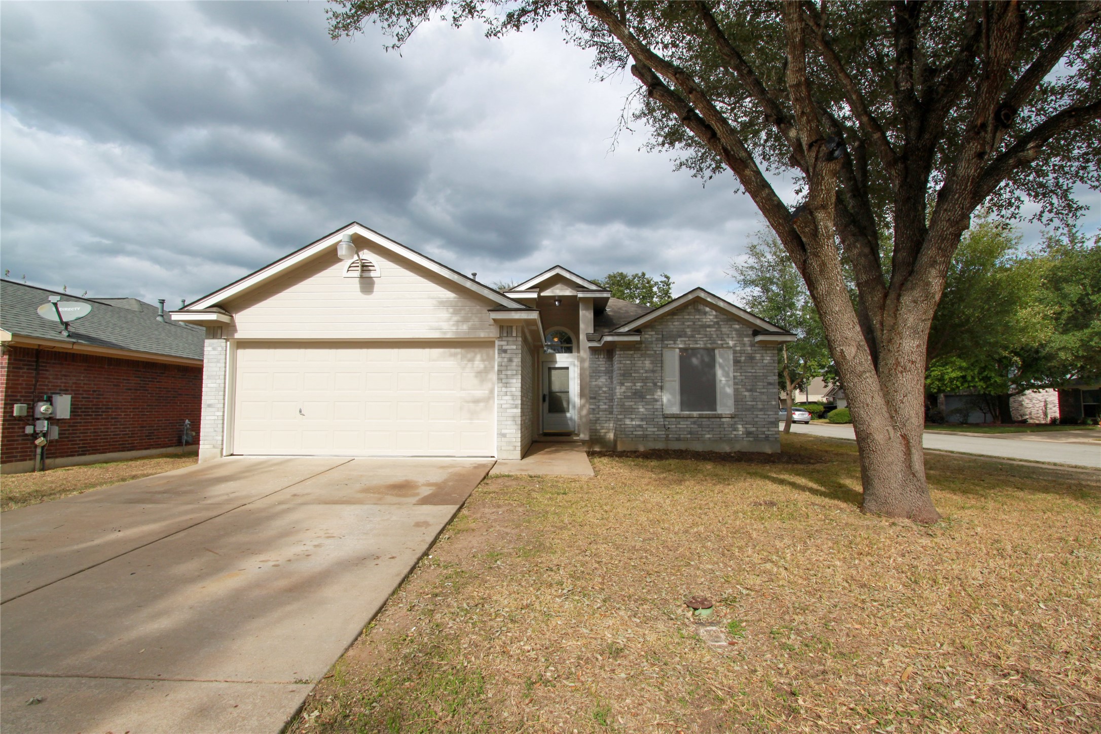 Single story home featuring concrete driveway, brick siding, an attached garage, and a front lawn