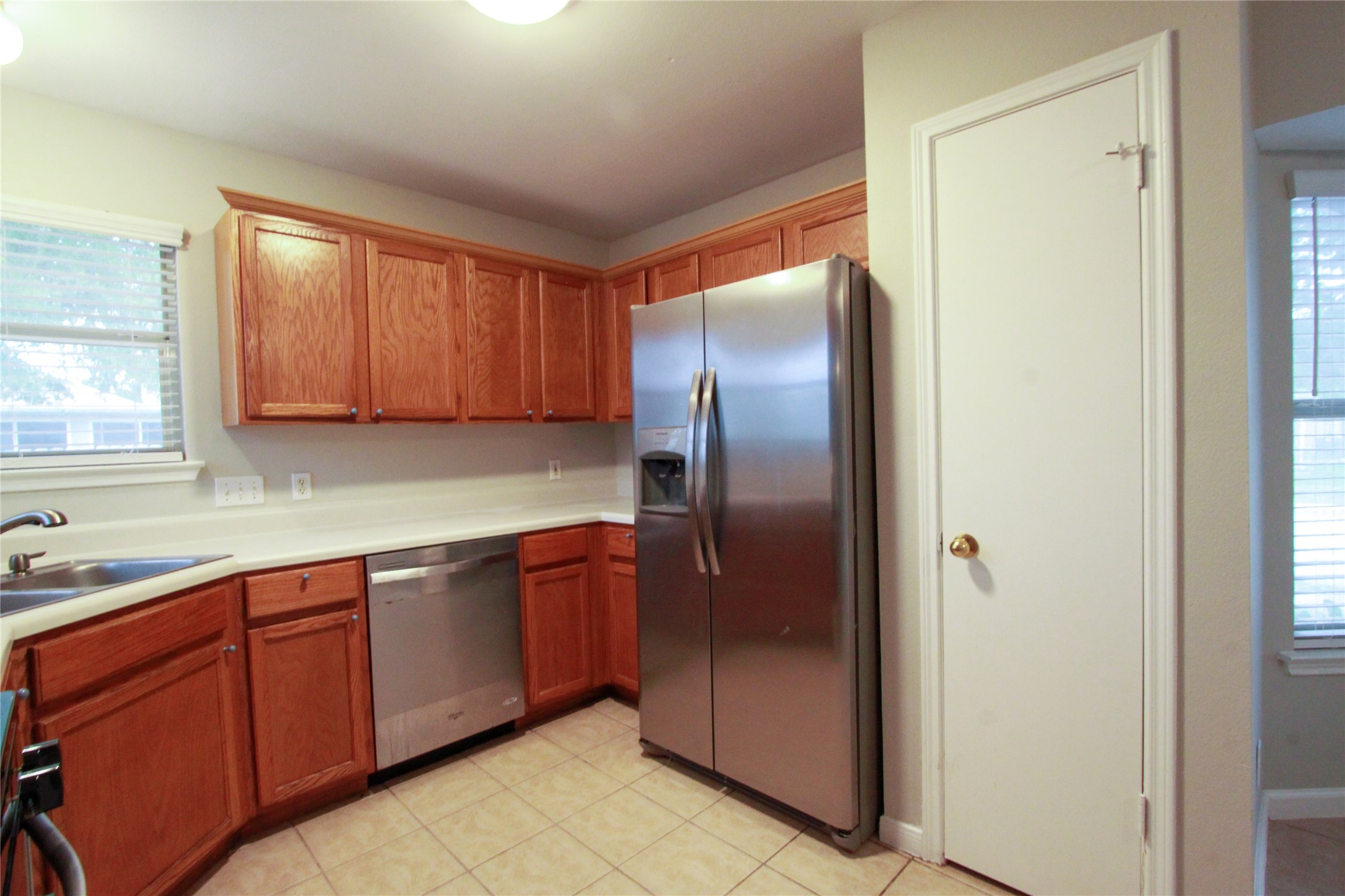 14708 Highsmith Street Austin, TX 78725 - Photo 13 of 28 Kitchen featuring stainless steel appliances, light countertops, wood finish cabinetry, and light tile patterned floors