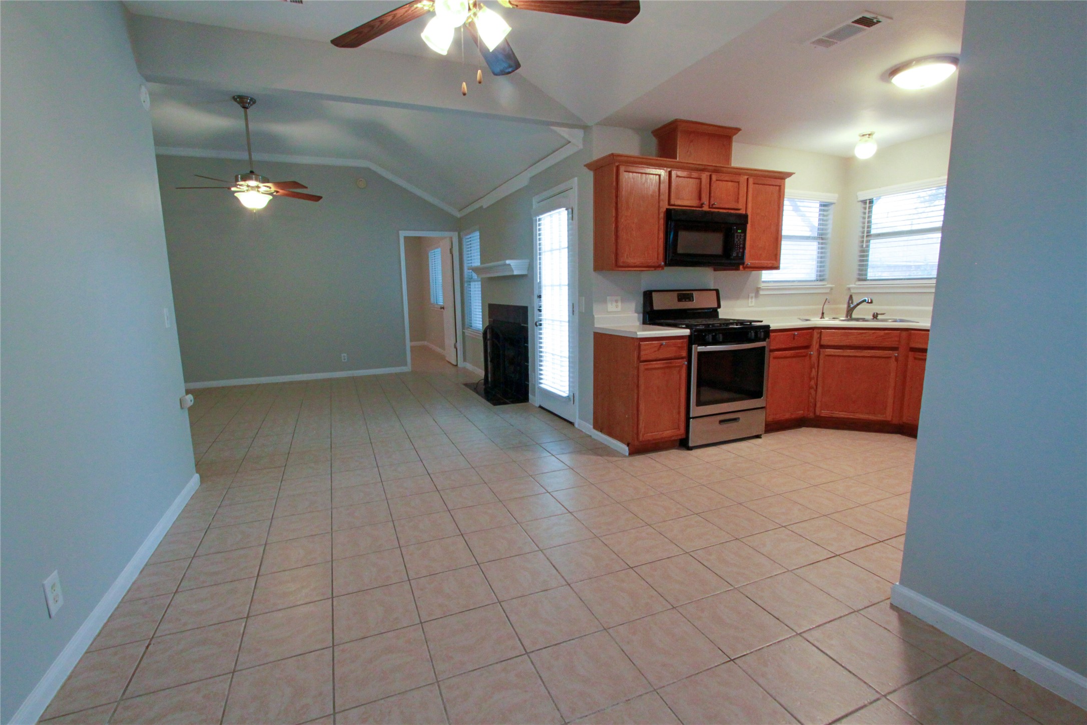 14708 Highsmith Street Austin, TX 78725 - Photo 15 of 28 Kitchen with light countertops, stainless steel gas range oven, a ceiling fan, wood finish cabinets, and black microwave