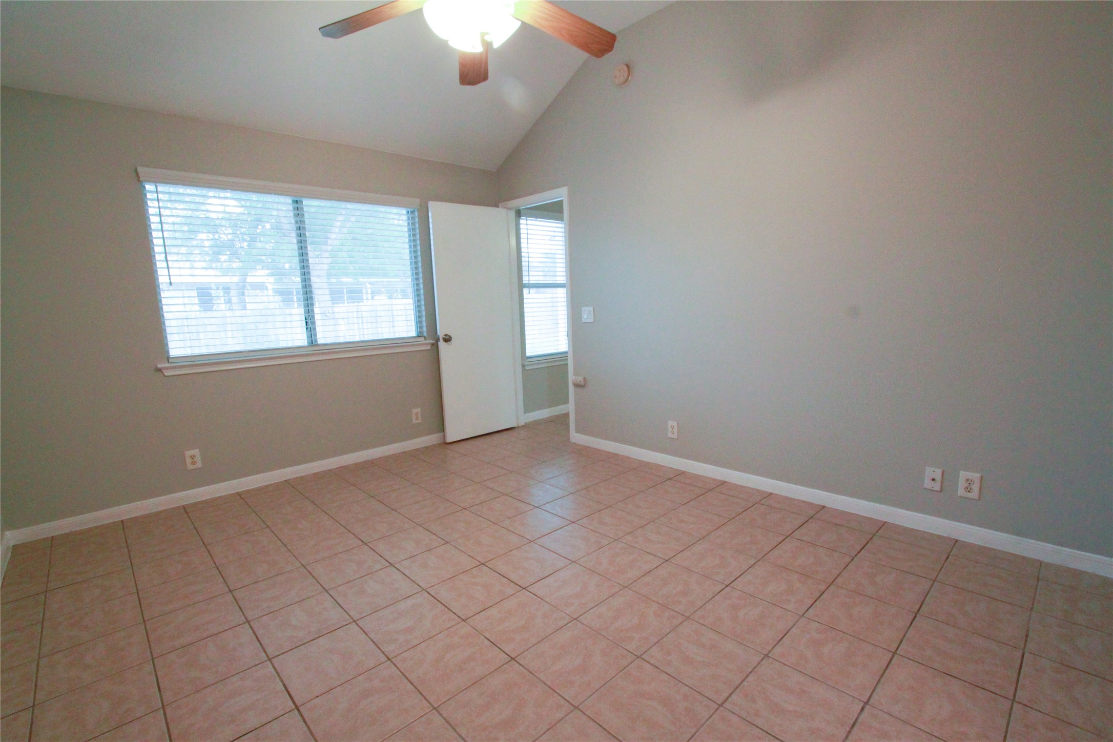 14708 Highsmith Street Austin, TX 78725 - Photo 17 of 28 Spare room featuring light tile patterned flooring, healthy amount of natural light, vaulted ceiling, and a ceiling fan