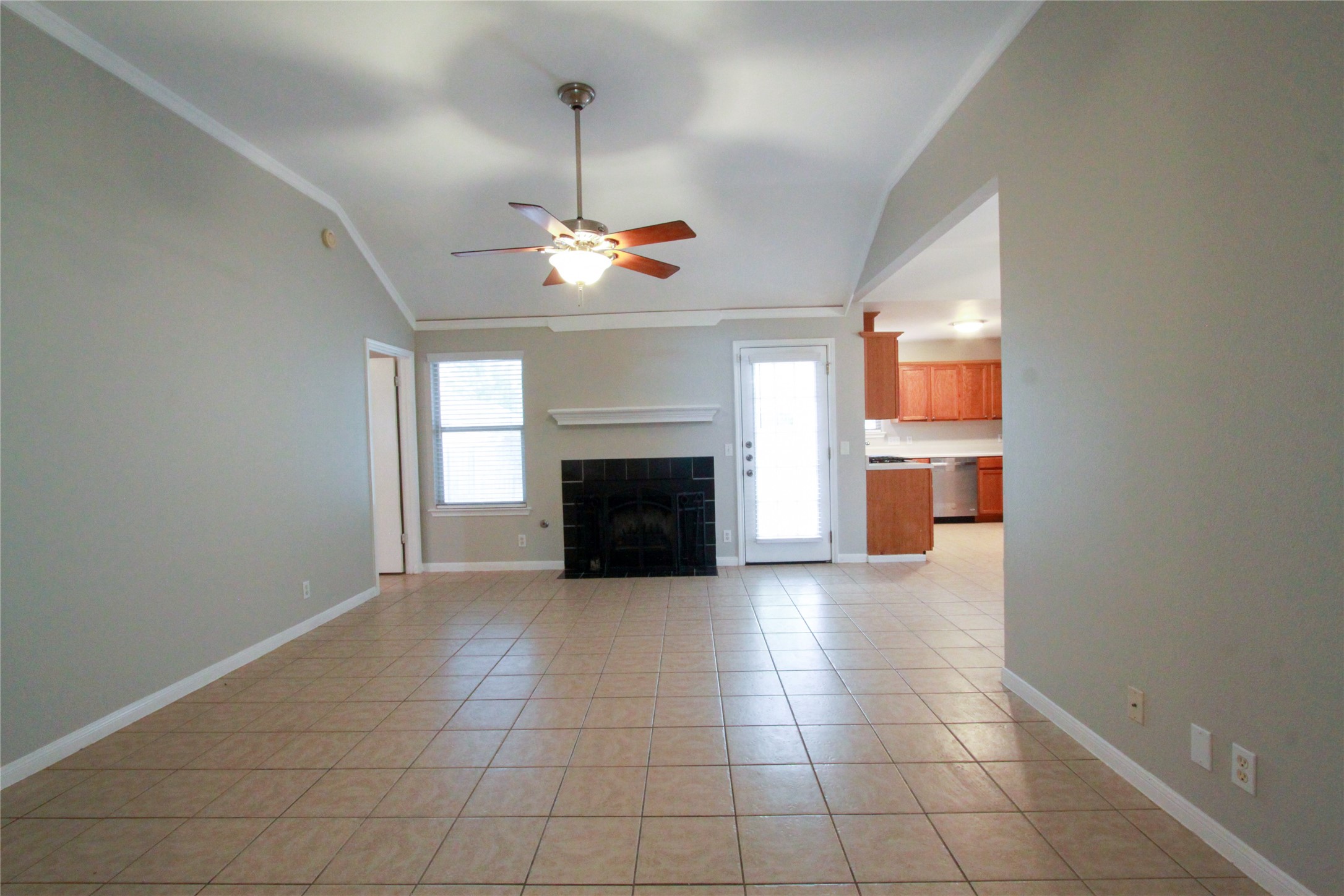 14708 Highsmith Street Austin, TX 78725 - Photo 4 of 28 Unfurnished living room with ornamental molding, a tile fireplace, light tile patterned flooring, a ceiling fan, and vaulted ceiling