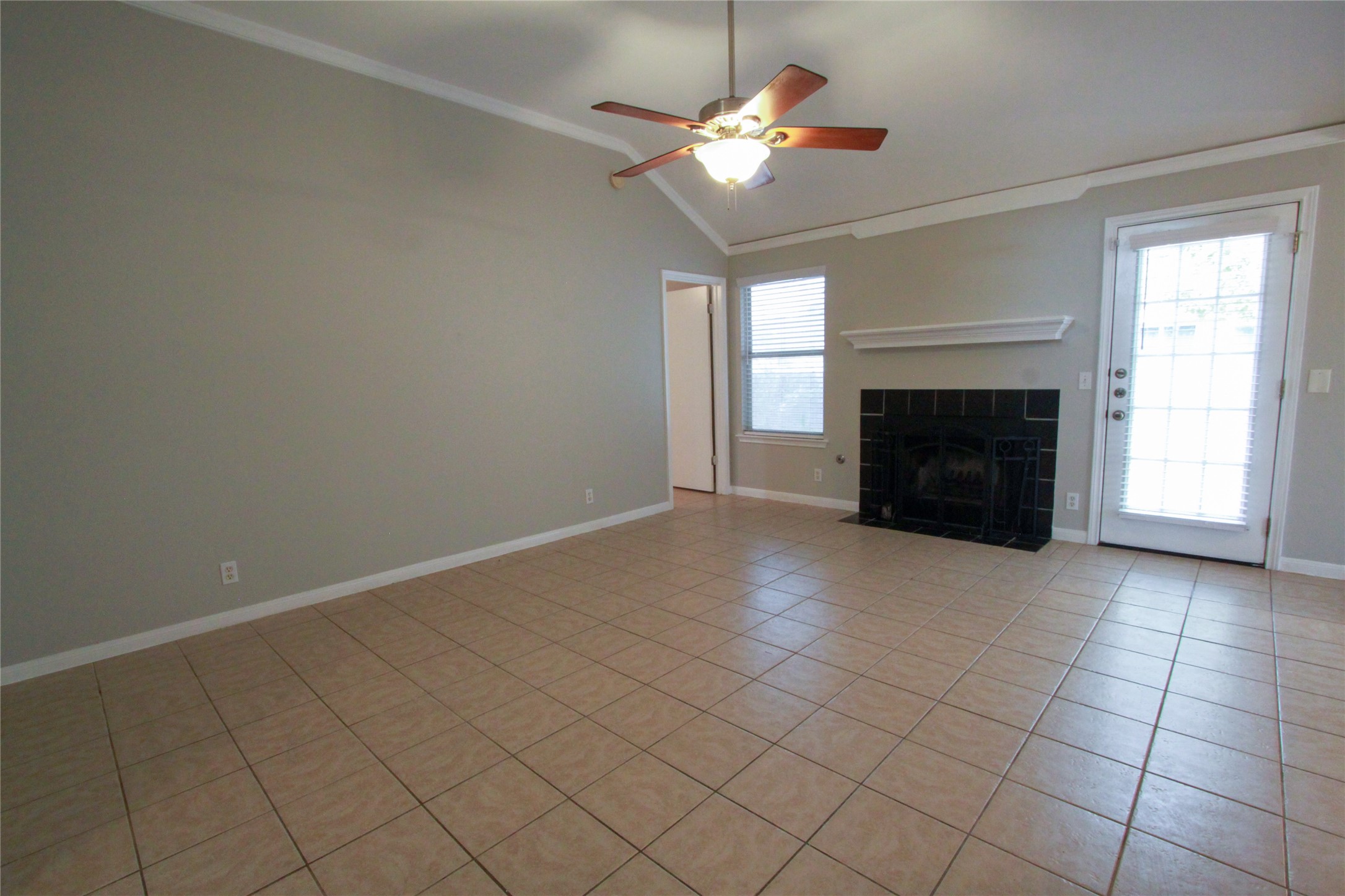 14708 Highsmith Street Austin, TX 78725 - Photo 5 of 28 Unfurnished living room with crown molding, light tile patterned floors, a tile fireplace, ceiling fan, and lofted ceiling