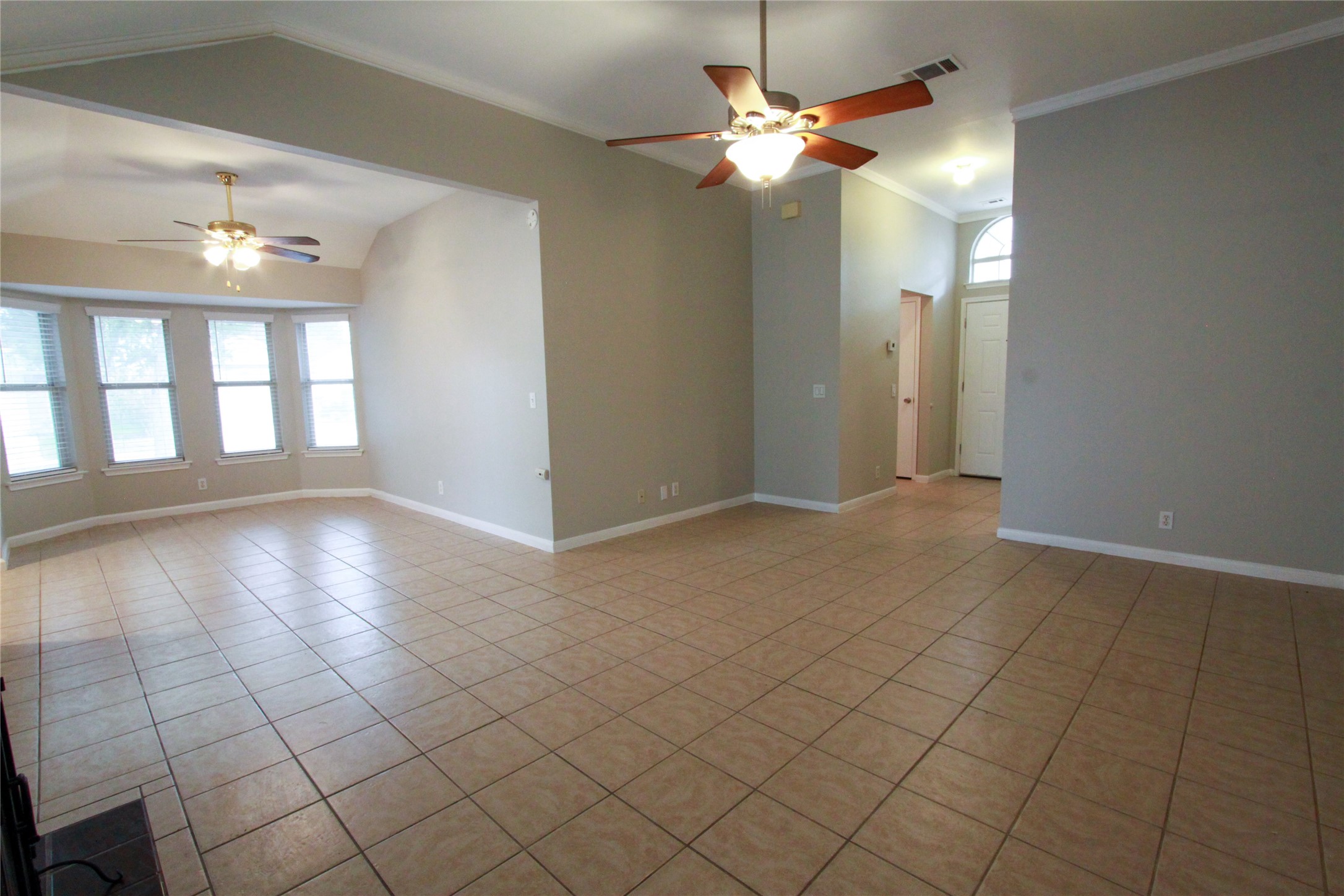 14708 Highsmith Street Austin, TX 78725 - Photo 7 of 28 Empty room with a ceiling fan, light tile patterned floors, ornamental molding, and lofted ceiling