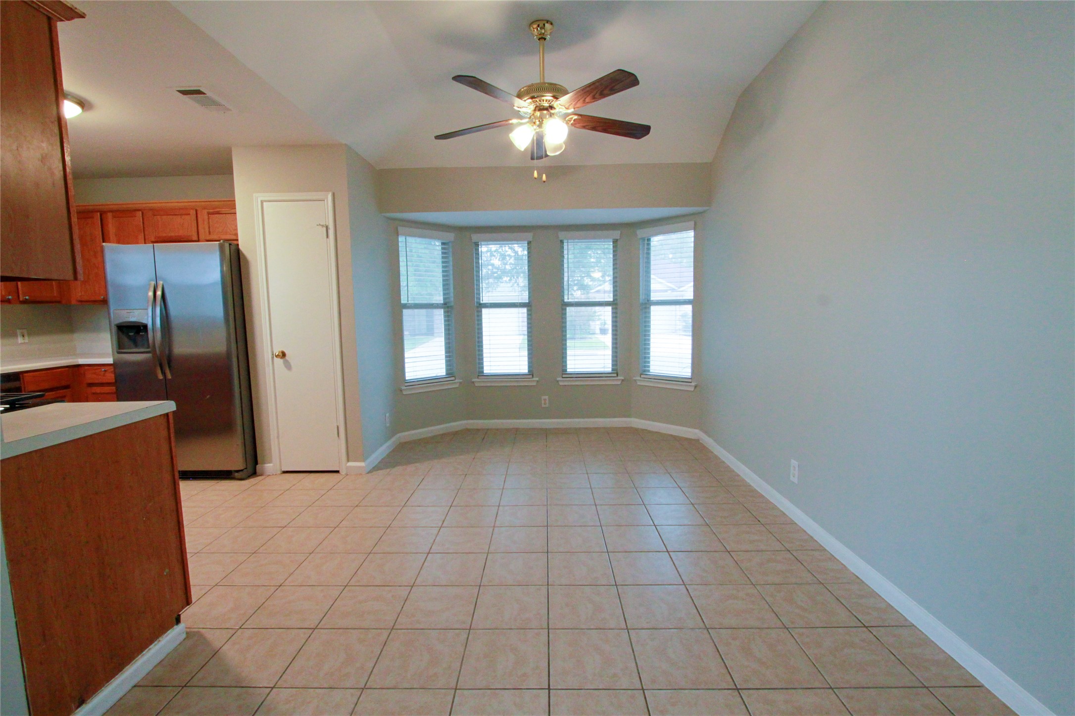 14708 Highsmith Street Austin, TX 78725 - Photo 9 of 28 Kitchen featuring stainless steel fridge, wood finish cabinets, light countertops, a ceiling fan, and light tile patterned floors