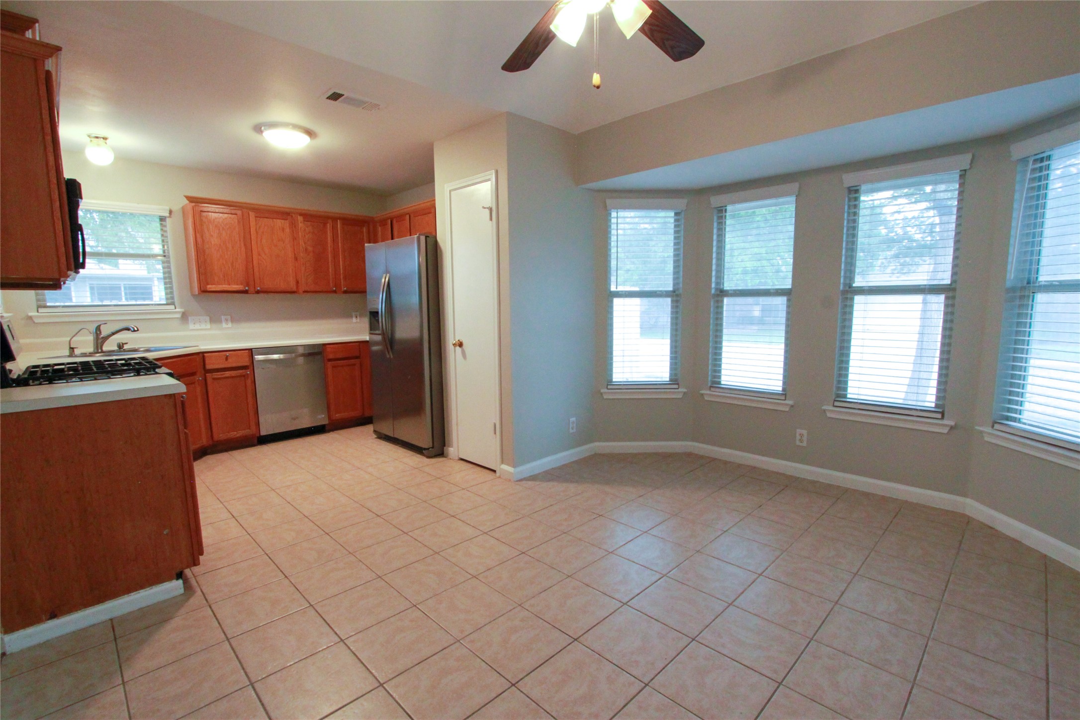14708 Highsmith Street Austin, TX 78725 - Photo 10 of 28 Kitchen featuring wood finish cabinets, light countertops, ceiling fan, stainless steel appliances, and light tile patterned floors