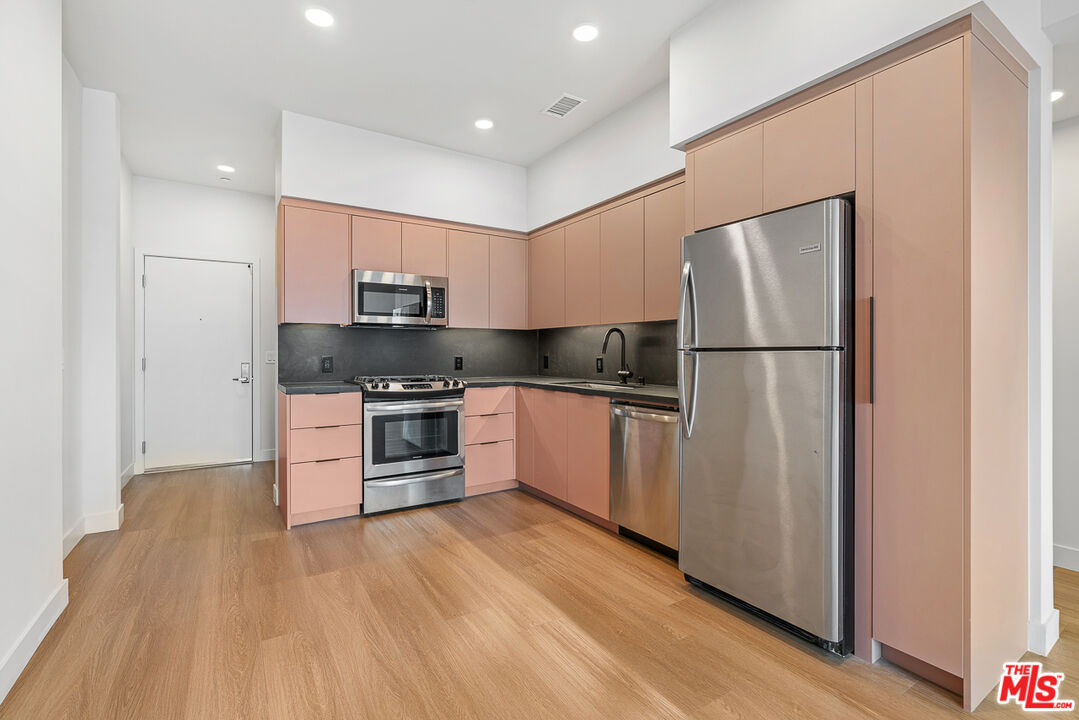 10601 Washington Boulevard, Unit 217 Culver City, CA 90232 - Photo 7 of 29 a kitchen with a refrigerator a stove top oven and wooden floor
