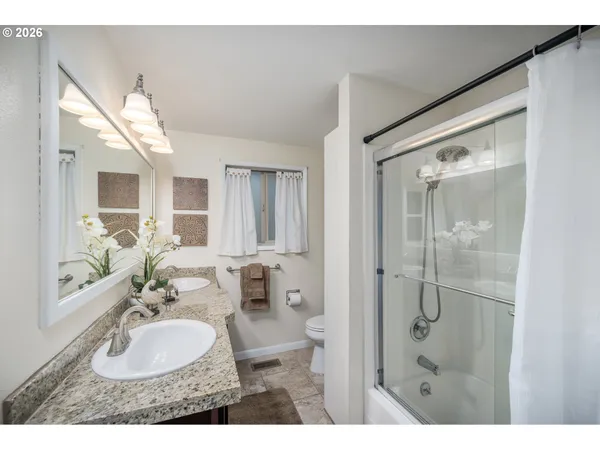 a bathroom with a granite countertop sink mirror and a shower
