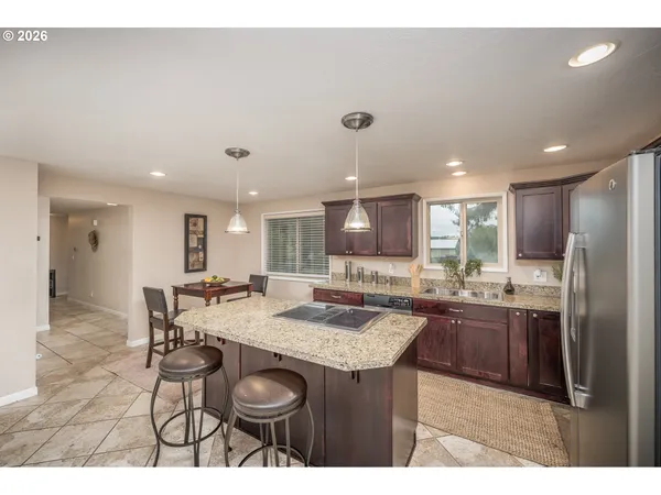 a kitchen with stainless steel appliances kitchen island granite countertop a table chairs and a refrigerator