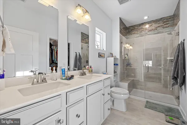 a bathroom with a double vanity sink toilet mirror and shower