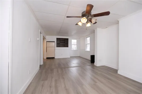 a view of an empty room with window and wooden floor