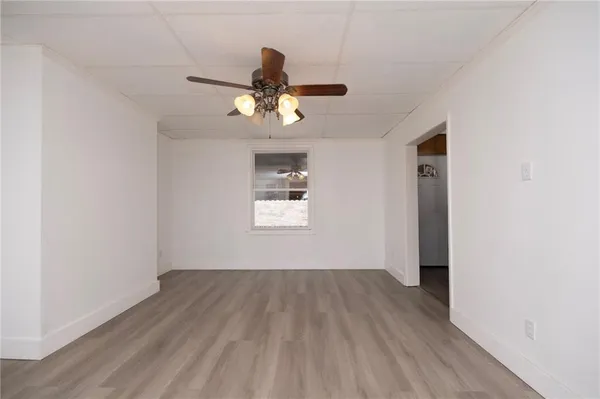 a view of a room with wooden floor ceiling fan and window