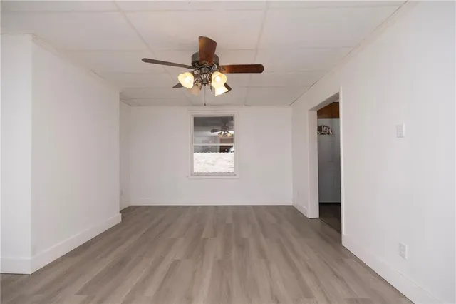 a view of a room with wooden floor ceiling fan and window