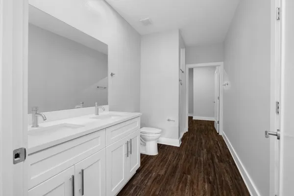 a spacious bathroom with a granite countertop sink toilet a large mirror and a shower