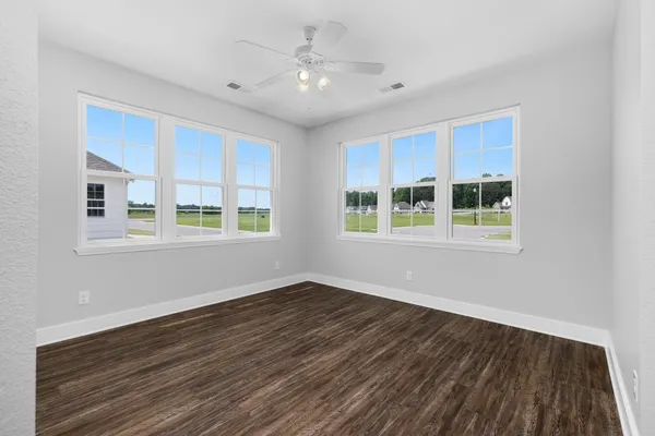 a view of an empty room with window and wooden floor