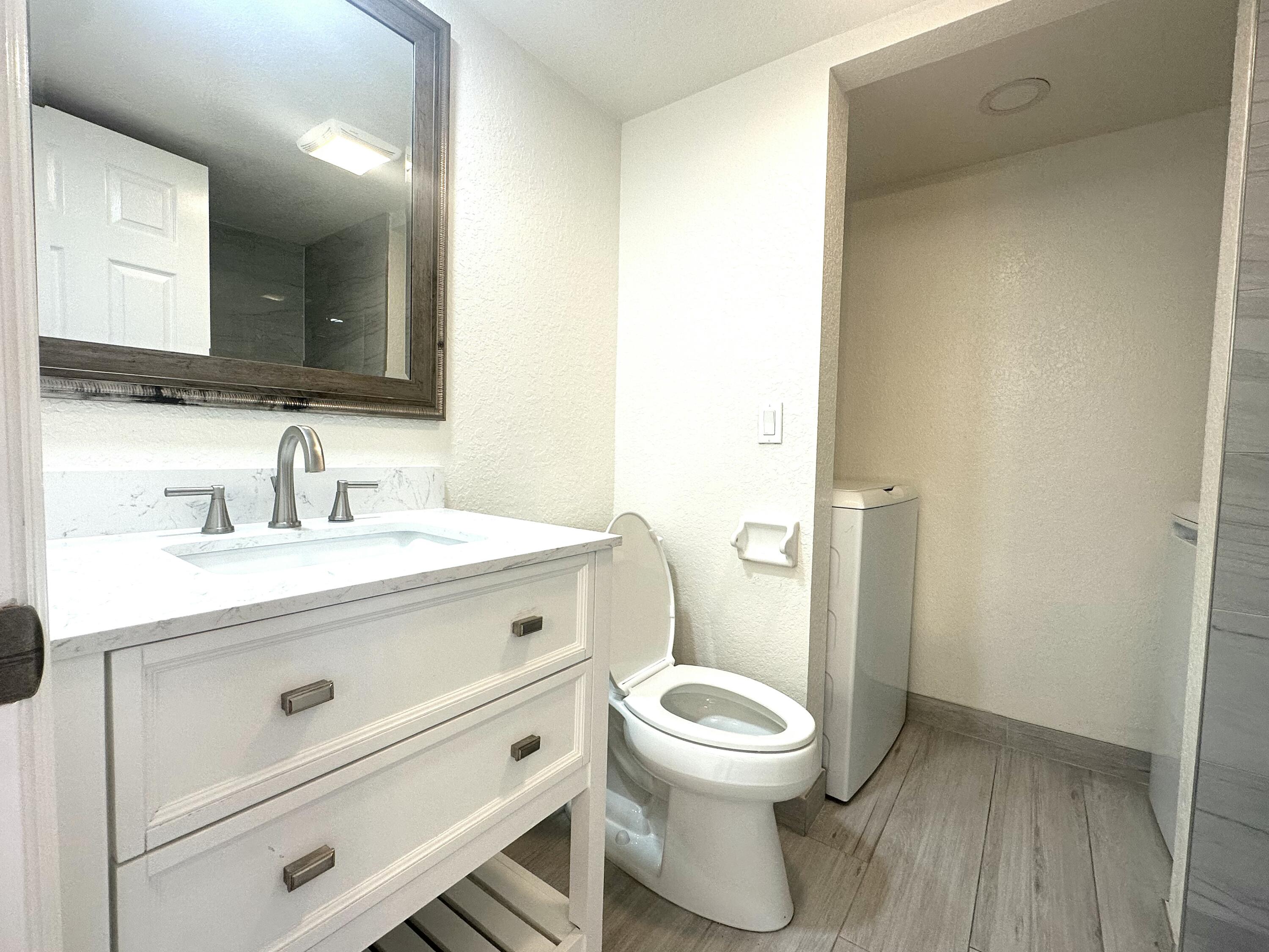 282 Arabian Road Palm Springs, FL 33461 - Photo 14 of 26 a bathroom with a toilet a sink and mirror