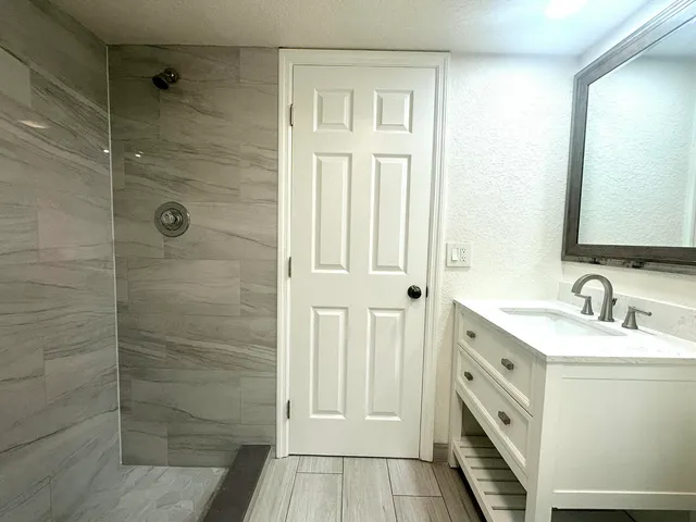 a bathroom with a granite countertop sink a mirror and a shower