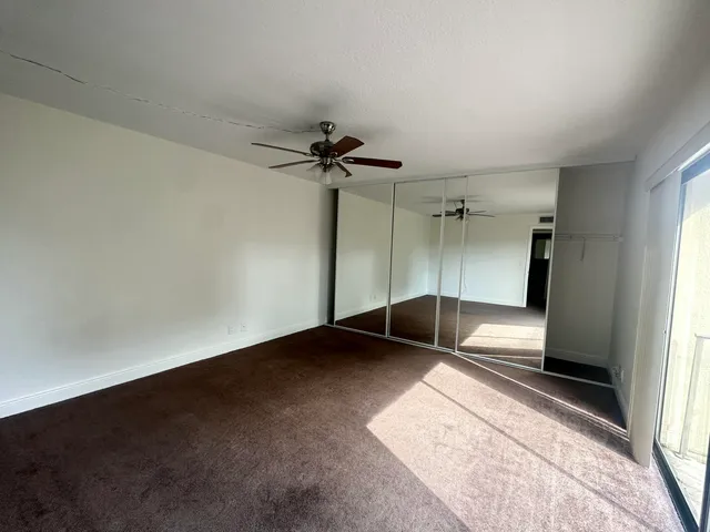 an empty room with a ceiling fan and window