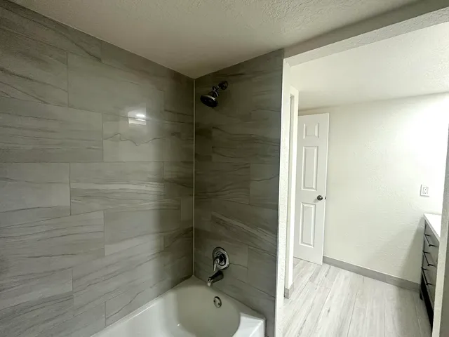 a bathroom with a tub shower and sink