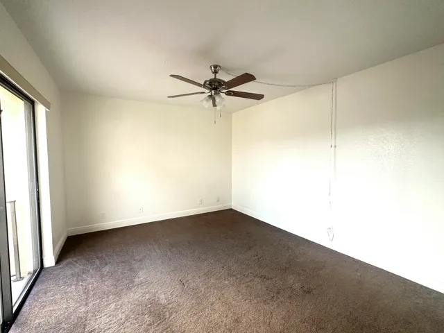 an empty room with a ceiling fan and a window