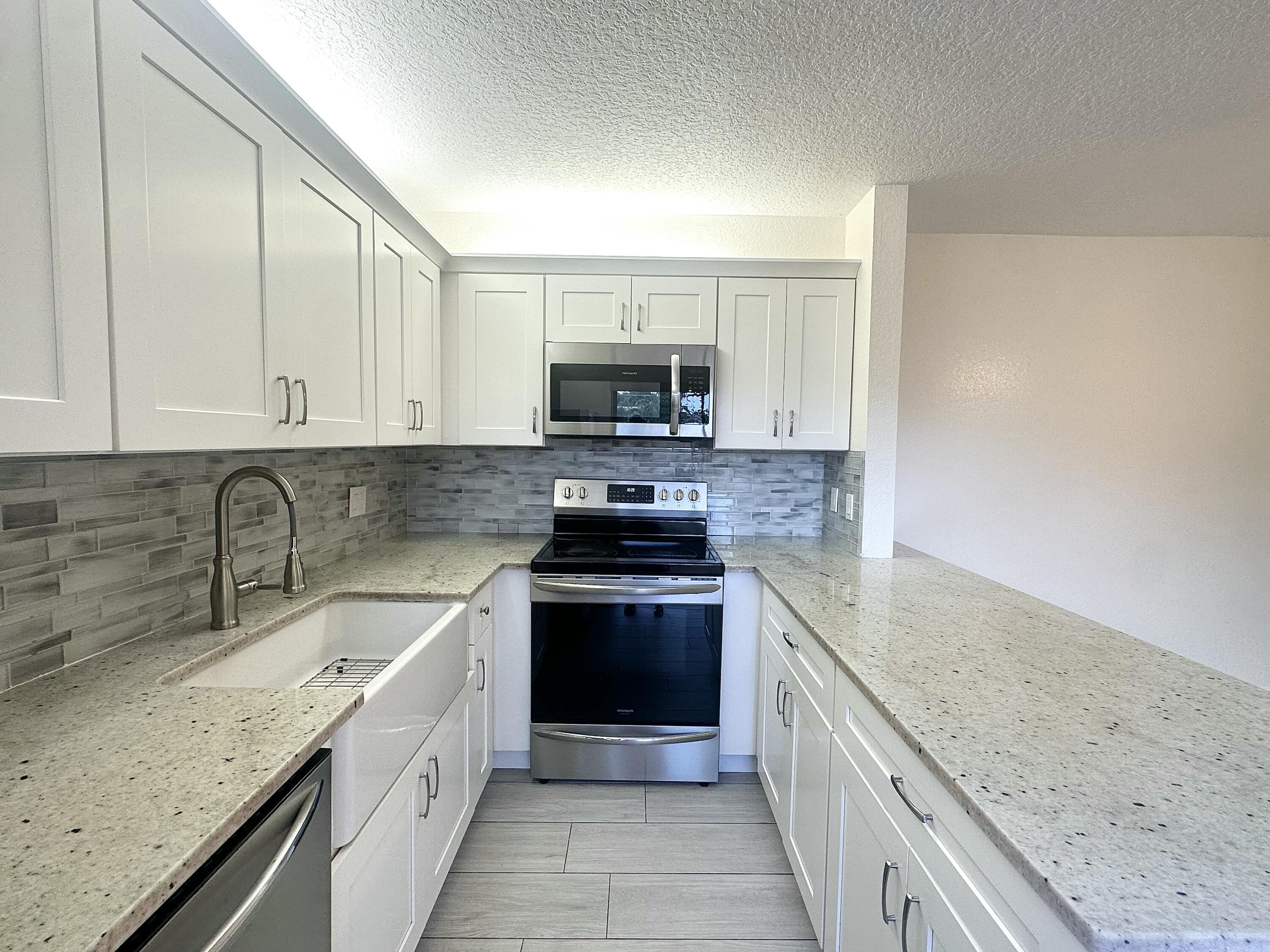 282 Arabian Road Palm Springs, FL 33461 - Photo 8 of 26 a kitchen with granite countertop a sink and a stove top oven