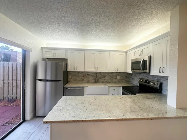 a kitchen with stainless steel appliances granite countertop a refrigerator a stove and a sink