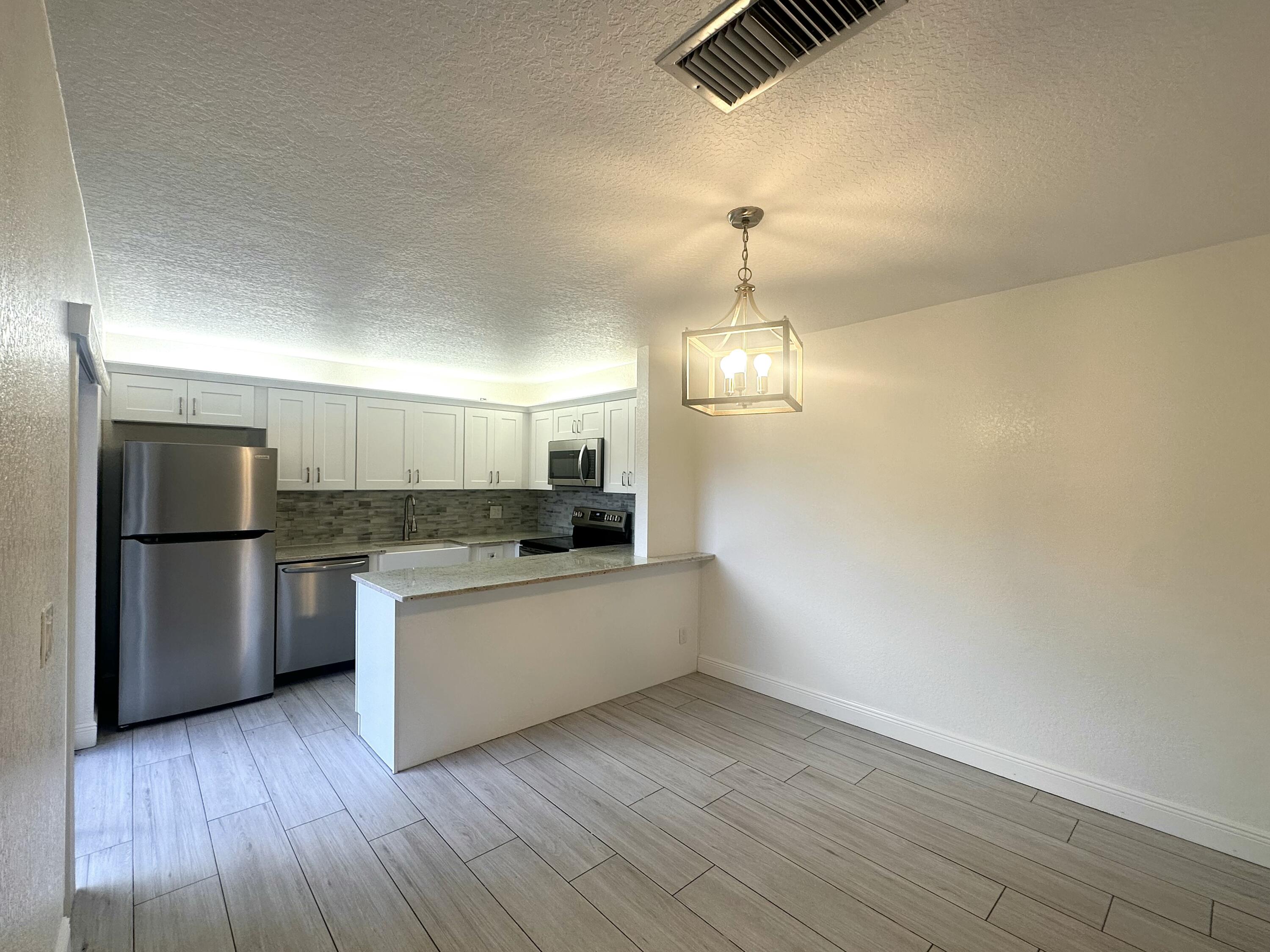 282 Arabian Road Palm Springs, FL 33461 - Photo 10 of 26 a kitchen with a refrigerator and a stove top oven