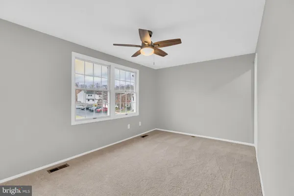 an empty room with windows and fan