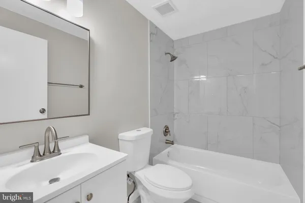 a bathroom with a toilet a sink a mirror a bathtub and vanity