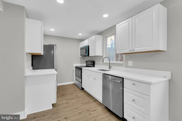a kitchen with a sink a stove a refrigerator and white cabinets