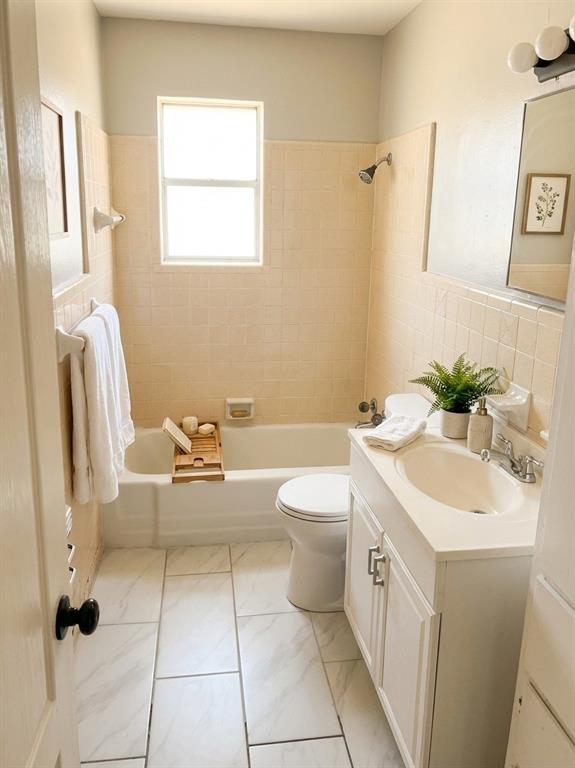 1910 Mercedes Road Denton, TX 76205 - Photo 3 of 5 Bathroom featuring vanity, tile walls, tub / shower combination, and light marble finish floors