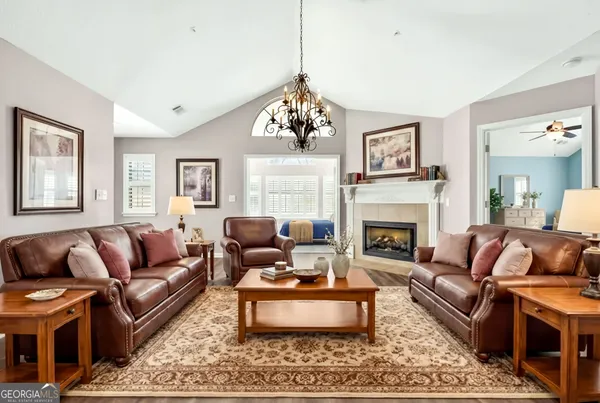 a living room with furniture a fireplace and a chandelier