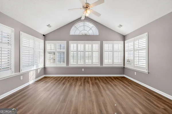 a view of an empty room with wooden floor and a window