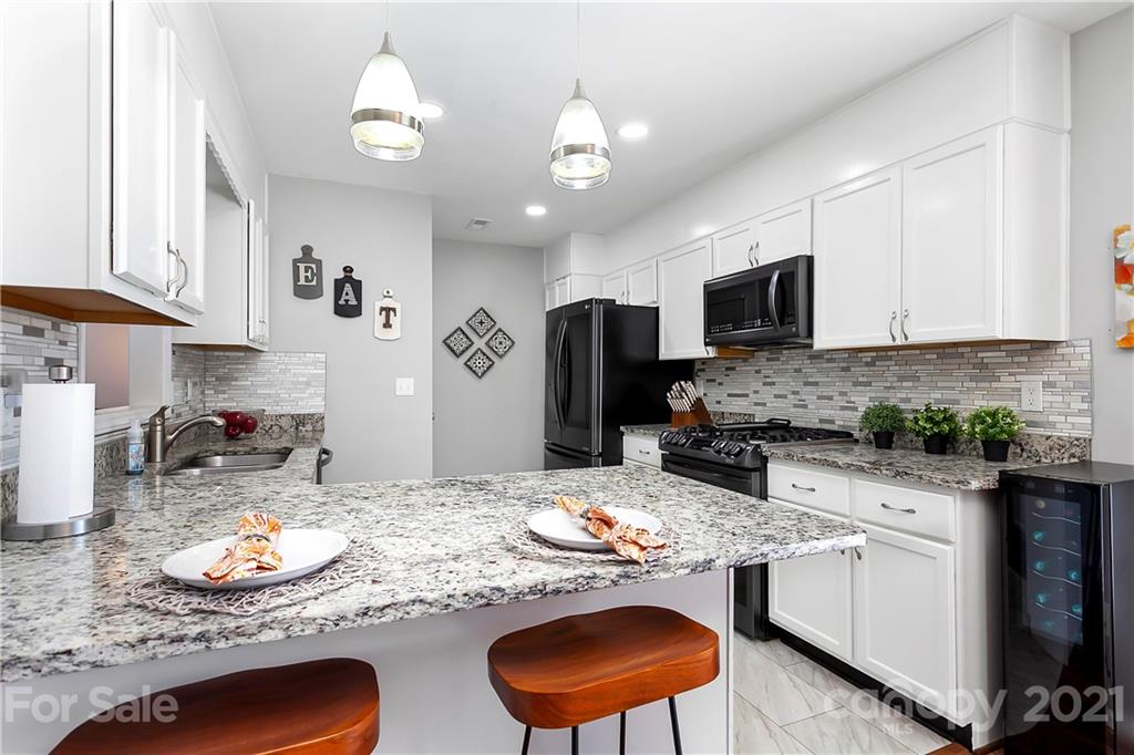 5063 Suwarrow Circle Tega Cay, SC 29708 - Photo 6 of 18 a kitchen with stainless steel appliances granite countertop a sink a stove a refrigerator cabinets and living room