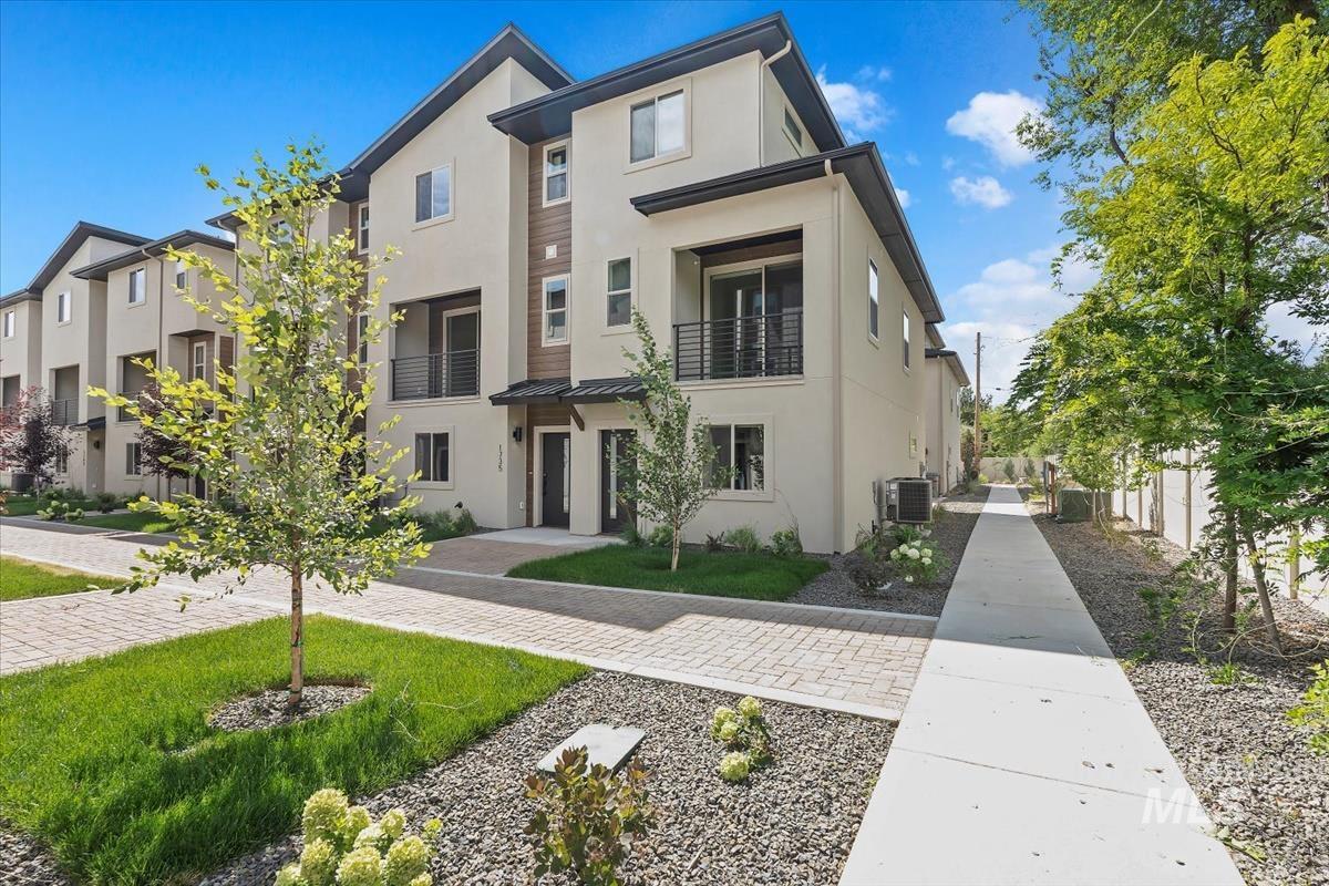 View of front of home with stucco siding, a balcony, a standing seam roof, and a metal roof