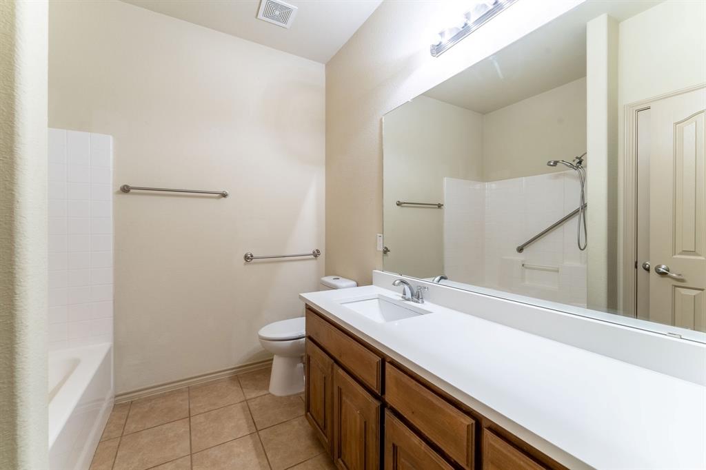 11156 Hawks Landing Road Fort Worth, TX 76052 - Photo 10 of 30 Bathroom featuring a wood-finish vanity with an integrated sink, a full-width mirror, tile flooring, and a tub/shower combination with grab bars