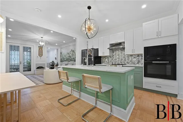 a large kitchen with stainless steel appliances granite countertop a stove a sink a microwave and a dining table with wooden floor