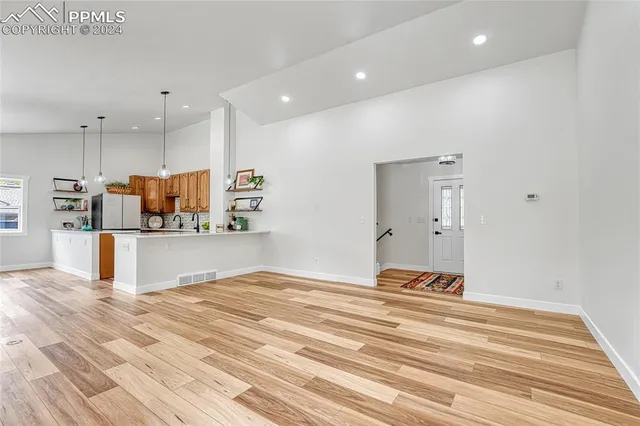 a large white kitchen with wooden floor and a sink
