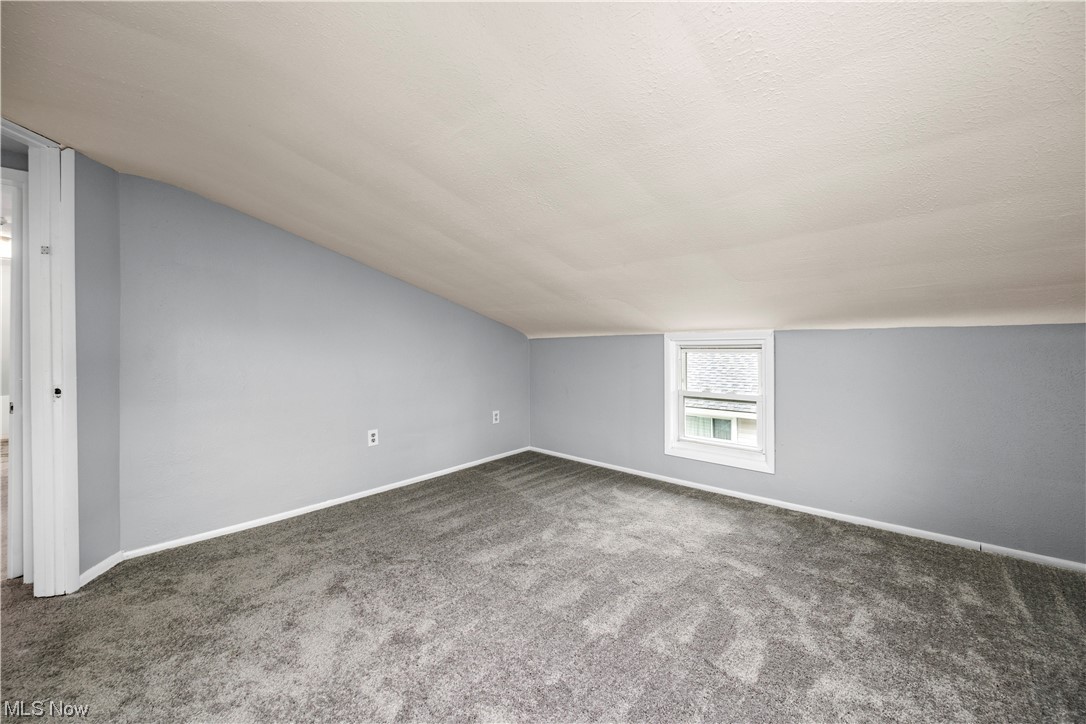 9284 Berkshire Road Parma Heights, OH 44130 - Photo 10 of 17 Bonus room featuring a textured ceiling, dark carpet, and lofted ceiling