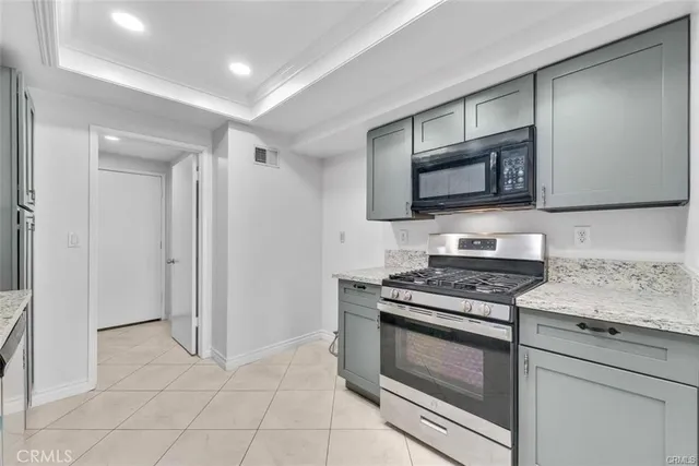 a kitchen with granite countertop a stove and a microwave with cabinets