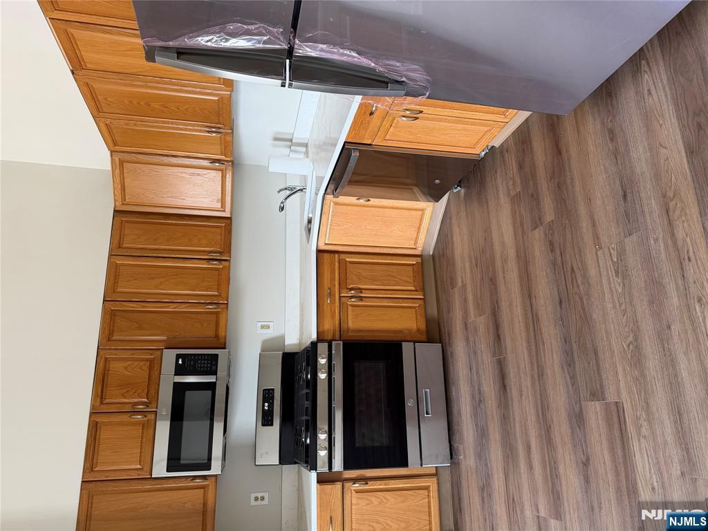 250 Park Avenue, Unit 1 East Rutherford, NJ 07073 - Photo 3 of 8 a kitchen with stainless steel appliances wooden cabinets a stove a microwave and a view of living room