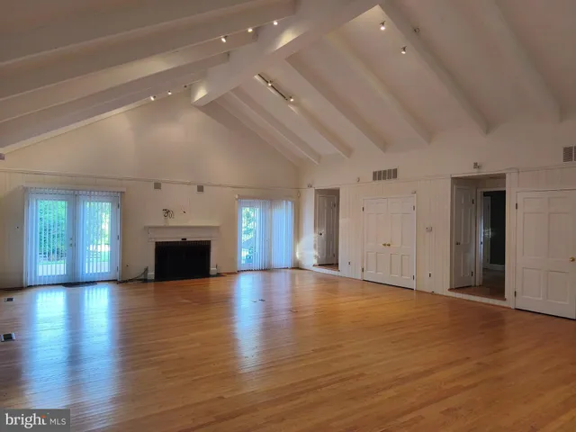 an empty room with wooden floor fireplace and windows