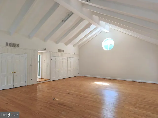 a view of an empty room with window and wooden floor