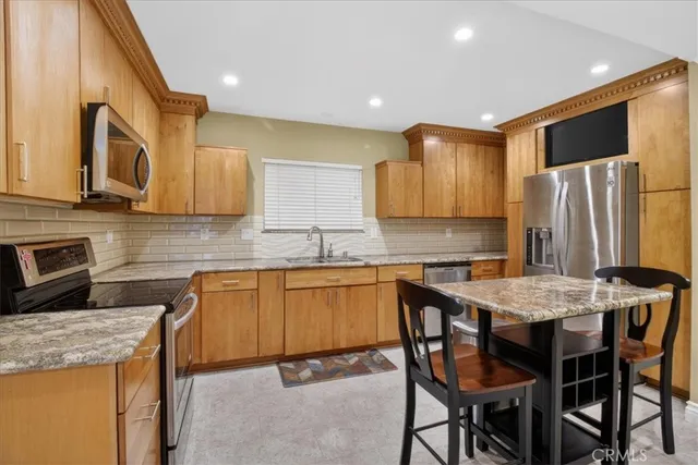 a kitchen with stainless steel appliances granite countertop a table chairs sink refrigerator and microwave