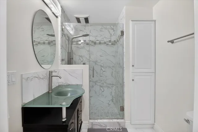 a bathroom with a granite countertop sink a mirror and shower