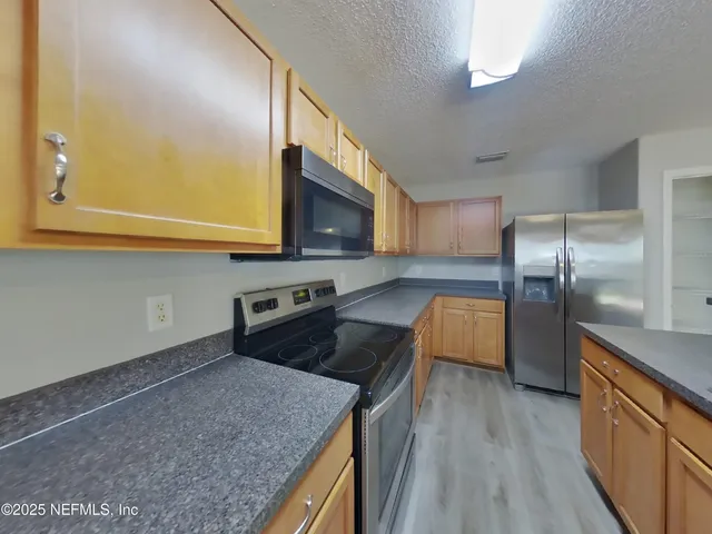 a kitchen with granite countertop a sink a counter space stainless steel appliances and cabinets