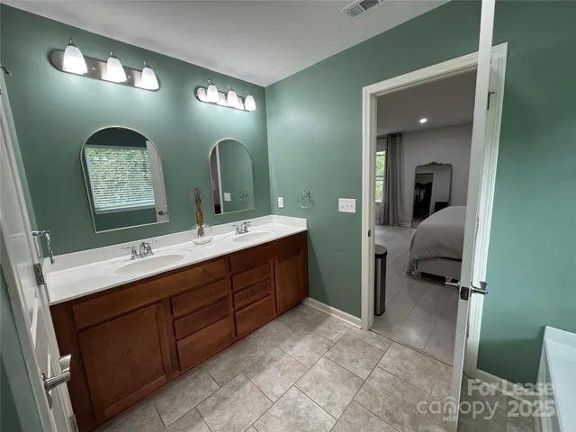 a en suite bathroom with a double vanity sink and a mirror
