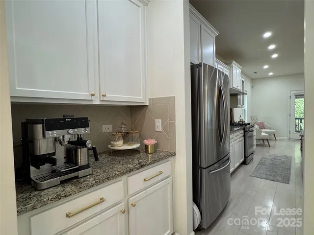 a kitchen with granite countertop a refrigerator and stainless steel appliances